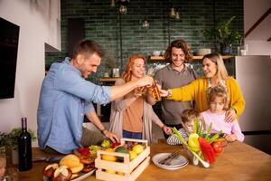 twee gezinnen roosteren met cider terwijl voorbereidingen treffen avondeten in de keuken foto