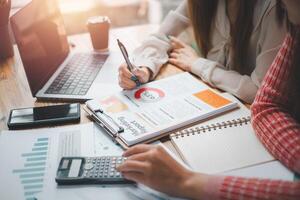 groep zakenmensen analyse samenvattende grafiekrapporten van bedrijfskosten en werkgegevens over de financiële overzichten van het bedrijf. foto