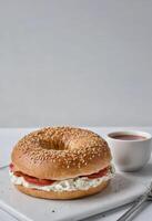 ai gegenereerd een bagel met room kaas en tomaat Aan wit bord foto