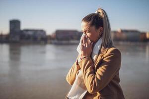 vrouw blazen neus- terwijl zittend door de rivier- Aan een zonnig winter dag. afgezwakt afbeelding. foto