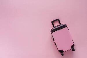 mini pink bagage speelgoed- model- Aan roze pastel gekleurde achtergrond foto