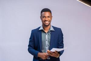 dichtbij omhoog van een knap Afrikaanse zakenman glimlachen net zo hij houden het dossier in zijn hand- foto