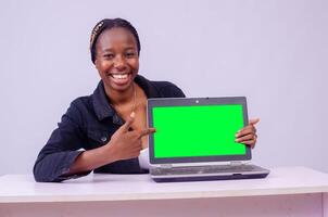 portret van een mooi jong zwart vrouw tonen haar laptop scherm foto