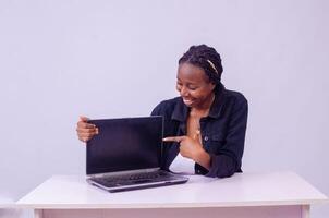 portret van een opgewonden mooi jong zwart vrouw richten naar haar laptop scherm foto