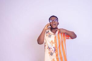 jong zwart Afrikaanse jongen staand Aan een wit studio muur maken oproepen met zijn mobiel telefoon lachend uit foto