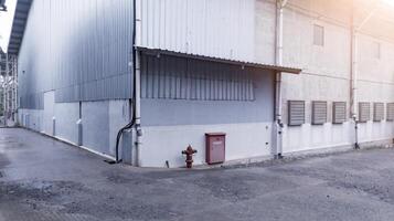 industrieel gebouw met staal dak bouw en geïnstalleerd uitlaat fans Aan de muur, en met hydrant installatie. foto