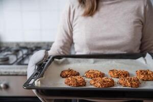 vrouw Holding bakken dienblad met klaar koekjes. foto