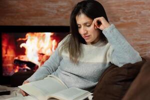 vrouw getrokken naar de verhaal van een boek in de comfort van haar huis. foto