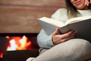 detailopname van vrouw lezing een boek in de warmte van haar huis. foto
