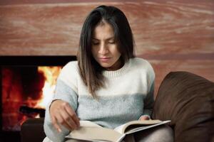 vrouw getrokken naar de verhaal van een boek in de comfort van haar huis. foto