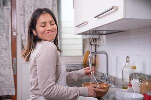 vrouw heeft pret terwijl voorbereidingen treffen koekjes Bij huis. foto