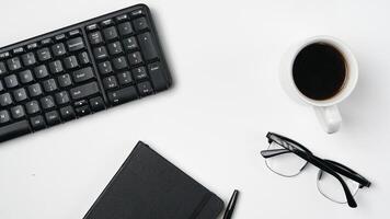 werkruimte bureau met notitieboekjes, pennen, toetsenbord, bril en koffie Aan wit achtergrond foto