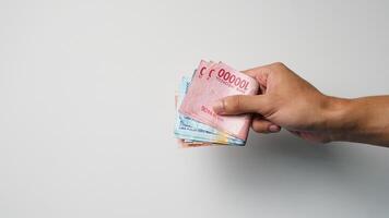 man's hand- Holding een dichtproppen van Indonesisch geld naar betalen contant geld foto