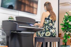 vrouw in jurk spelen piano in leven kamer, jong meisje spelen groots piano Bij huis foto