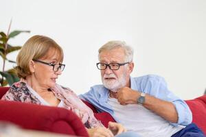 portret van een gelukkig senior koppel in de woonkamer, een oudere vrouw en een man die thuis op een gezellige bank ontspant, concepten voor gelukkige gezinnen foto