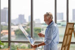 senior Mens Holding schilderen, ouderen Mens mannetje artiest tekening Bij kunst studio, gelukkig pensioen concepten foto