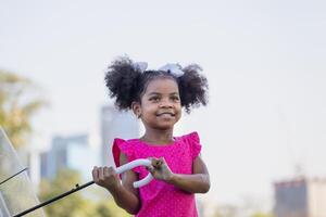 vrolijk kind meisje met een paraplu spelen met regen in de park, schattig weinig kind meisje spelen buitenshuis in de tuin foto