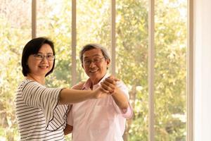 samen tijd doorbrengen thuis een bejaard Aziatisch stel dat plezier heeft met dansen in de woonkamer foto