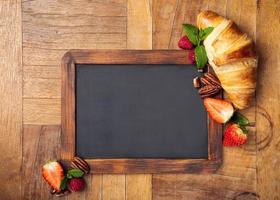 zwart krijtbord met croissant en bessen foto