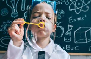 kind doet zeepbellen tegen van getekende schoolbord foto