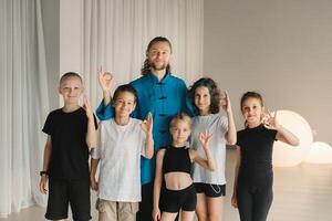 een gewricht portret van een yoga trainer en kinderen staand in een geschiktheid kamer foto