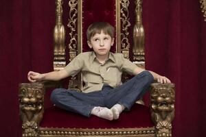 kind dromen in een Koninklijk rood stoel foto
