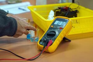 studenten gebruik een digitaal multimeter naar meten elektrisch potentieel verschillen in een chemie experiment Aan galvanisch cellen. zacht en selectief focus. foto