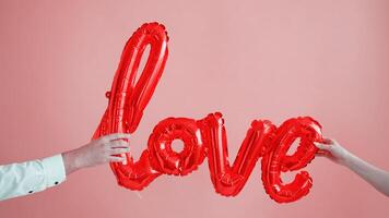 Mens en Dames met lucht ballonnen in vorm van woord liefde Aan roze achtergrond. Valentijnsdag dag viering foto