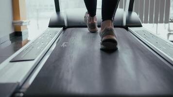 vrouw poten wandelen en rennen Aan loopband in Sportschool. jong vrouw oefenen gedurende cardio training. voeten van meisjes in sport schoenen opleiding binnen- Bij sport club. mensen joggen. dichtbij omhoog foto