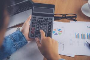 de accountant hand- is gebruik makend van de rekenmachine. voor kosten analyse winst en verlies en belasting berekening concept voorbereiding van financieel verklaringen foto