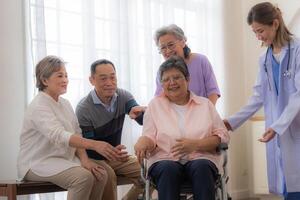 Aziatisch jong verpleegster ondersteuning paar senior ouder vrouw in een rolstoel. ouderen volwassen en een groep van senior vrienden leven in de ziekenhuis. gezelligheid van gepensioneerd mensen. foto