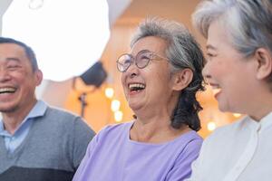 dichtbij omhoog senior vrouwtjes en mannetje zittend Aan bank. ouder mensen zijn luisteren en genieten vergadering focus groep Bij leven kamer. blij zorgeloos gepensioneerd senior vrienden genieten van ontspanning Bij bijna huis. foto