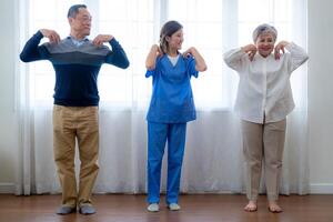 portret van ouderen glimlachen Aziatisch vrouw en mensen aerobics in kinderkamer huis. senioren zijn in beweging hun lichaam armen en schouders voor een gezond leven. gepensioneerd mensen activiteiten groep concept. foto