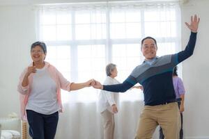 Aziatisch ouder mannetje en vrouwtjes mensen dans met hun partners Aan een dansen verdieping in leven ruimte. gelukkig ouder paar het uitvoeren van krijgen oefening. blij zorgeloos gepensioneerd senior vrienden genieten van ontspanning foto