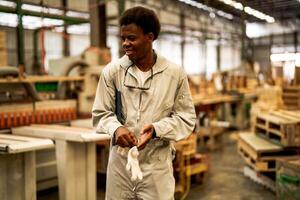 Afrikaanse Mens arbeiders bouwkunde staand met vertrouwen met werken suite jurk en hand- handschoen in voorkant machine. concept van slim industrie arbeider werkend. hout fabriek produceren hout gehemelte. foto