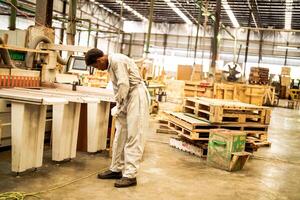 Afrikaanse Mens arbeiders bouwkunde staand met vertrouwen met werken suite jurk en hand- handschoen in voorkant machine. concept van slim industrie arbeider werkend. hout fabriek produceren hout gehemelte. foto