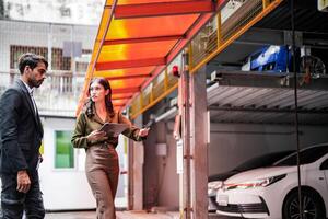 professioneel verkoper vrouw verkoop auto's naar zakenman koper. auto verkoop. manager geven suggesties naar zakenman koper in garage parkeren handel winkel. auto handelaar verkoop consultant. foto