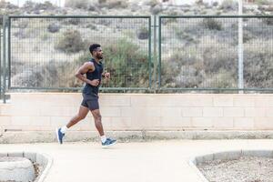 vastbesloten Afrikaanse Amerikaans atleet jogging in park gedurende training foto