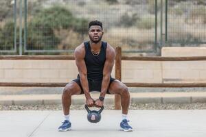 zwart sportman gehurkt met zwaar gewicht gedurende opleiding foto