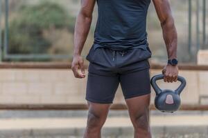 Bijsnijden Afrikaanse Amerikaans atleet Holding kettlebell foto