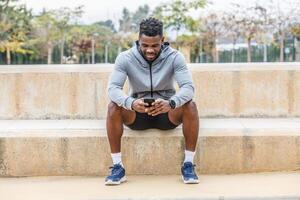 glimlachen zwart sportman chatten Aan smartphone na opleiding foto