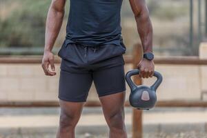 krachtig zwart Mens oefenen met kettlebell gedurende training foto