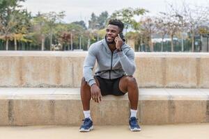 vrolijk zwart sportman sprekend via smartphone foto