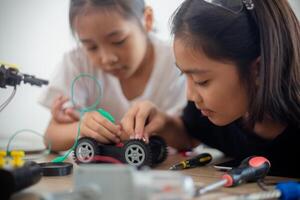 inventief kinderen leren Bij huis door codering robot auto's en elektronisch bord kabels in stang. construeren robot auto's Bij huis foto