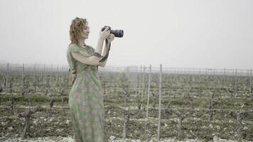 jong mooi vrouw duurt afbeeldingen in oogst veld. actie. kant visie van vrouw fotograaf in een veld- Aan grijs lucht achtergrond. foto