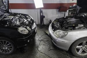 twee auto's met Open kappen zijn wezen gerepareerd in reparatie winkel gezicht naar gezicht foto