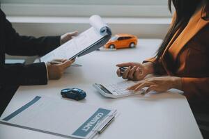 detailopname Aziatisch mannetje mensen auto verkoper of verkoop manager aanbiedingen naar verkopen een auto en legt uit en leest de voorwaarden van ondertekening een auto contract en verzekering. foto