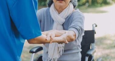 jong verpleegster of fysiotherapeut in scrubs helpen een gelukkig gepensioneerd oud vrouw Doen geschiktheid opdrachten met licht gewicht halters Bij huis. concept van fysiotherapie voor senioren foto