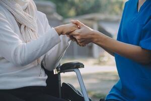 een verpleegster nemen zorg een senior mannetje Aan rolstoel in zijn tuin Bij huis foto