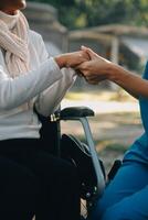 een verpleegster nemen zorg een senior mannetje Aan rolstoel in zijn tuin Bij huis foto